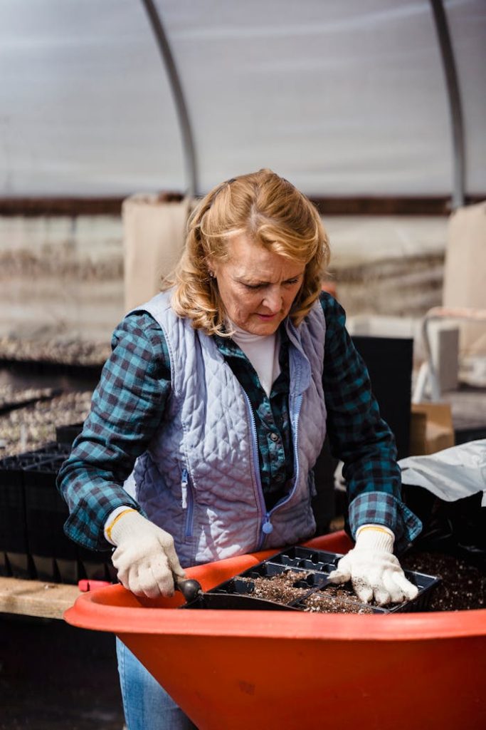 pexels-photo-7728377 A senior woman focuses on planting seeds in a greenhouse environment, showcasing gardening as a hobby.